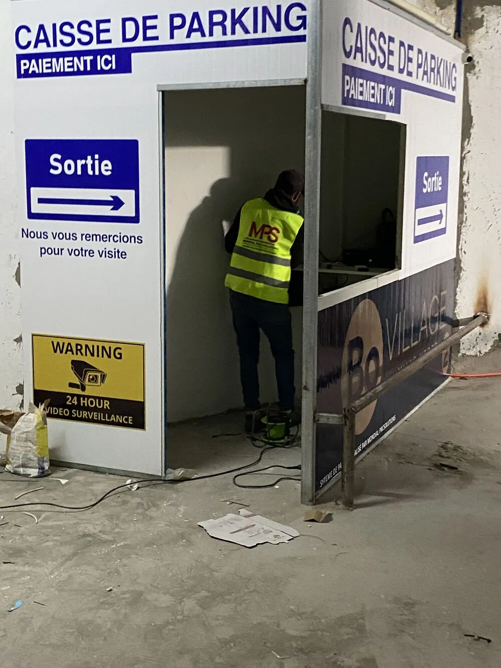 Caisse de parking « Paiement ici » avec signalétique de sortie et technicien MPS