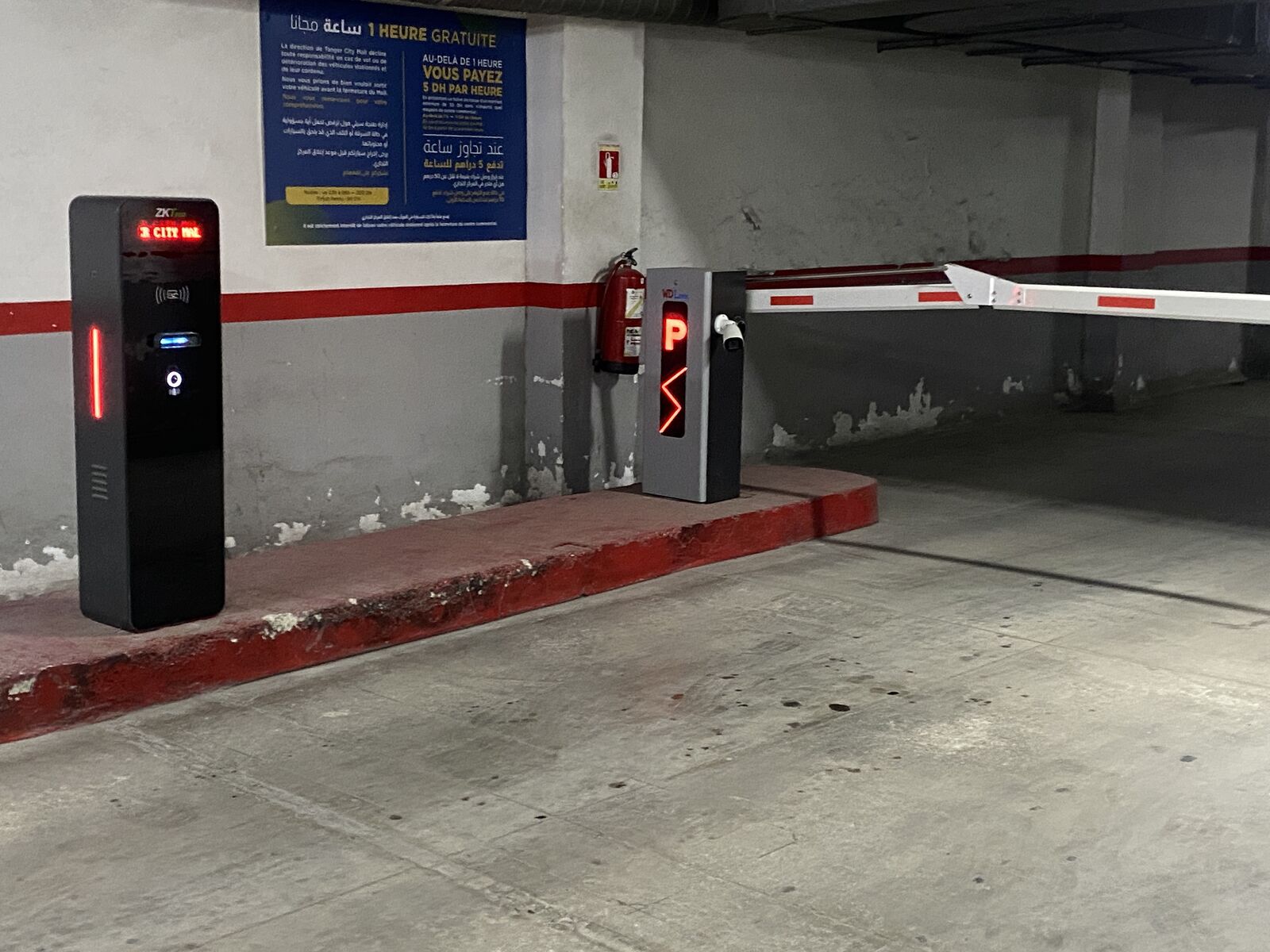 Entrée d’un parking payant à Tanger : borne distributrice de tickets avec afficheur LED et barrière automatique à indicateur lumineux P